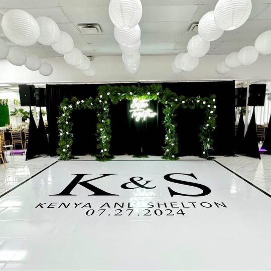 Monogram dance floor beneath a floral arch backdrop